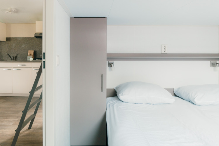Dormitorio y cocina modernos en la cabaña Veluwe lounge + sauna, Holiday park De Boshoek, Países Bajos.