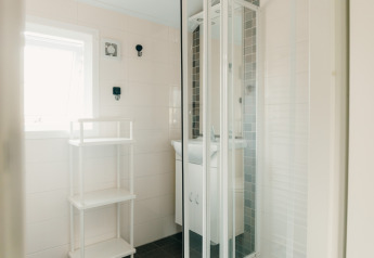 Salle de bain lumineuse à Veluwe lounge + sauna, Holiday park De Boshoek, avec douche et étagère.