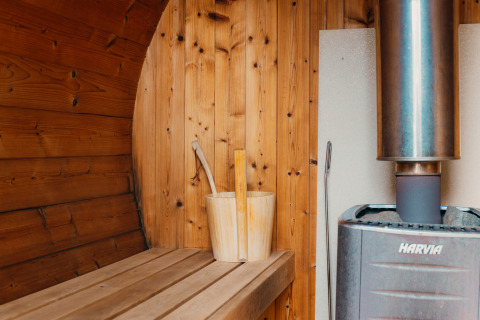 Interno sauna in legno con stufa, secchio e mestolo a Veluwe lounge + sauna, De Boshoek, Paesi Bassi.