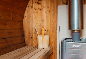 Innere Holzsauna mit Ofen, Eimer und Kelle in der Veluwe Lounge + Sauna, De Boshoek, Niederlande.
