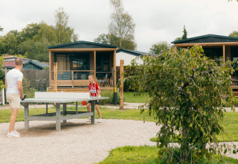 Deux personnes jouent au tennis de table en plein air devant des tiny houses au Holiday park De Boshoek, Pays-Bas.