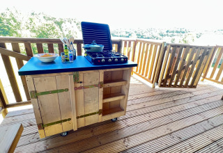 Outdoor kitchen setup on a wooden deck with stove and utensils at a glamping tent in Domaine La Barbe, France.