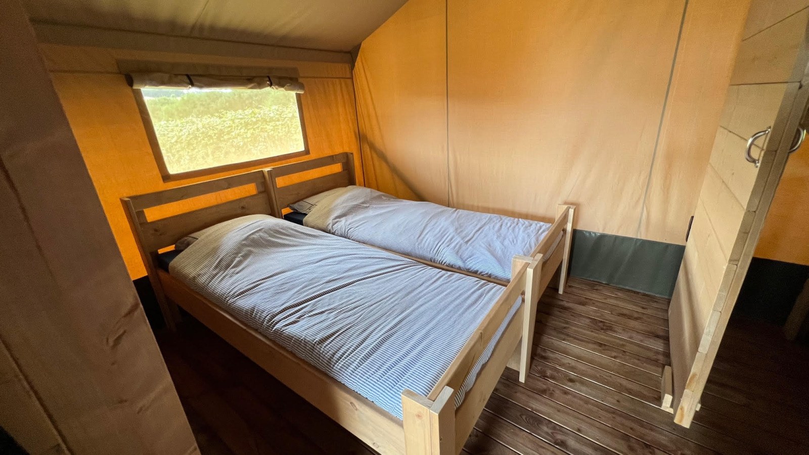 Interieur van een glamping safaritent op Domaine La Barbe in Frankrijk met twee houten eenpersoonsbedden.