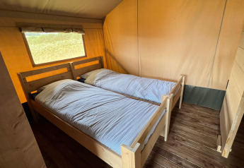 Intérieur d'une tente safari glamping au Domaine La Barbe en France avec deux lits simples en bois et sol en bois.