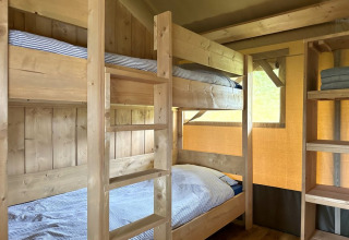 Houten stapelbedden in een glamping tent bij Domaine La Barbe in Frankrijk, sfeervol en knus ingericht.