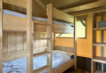 Letti a castello in legno in una tenda glamping al Domaine La Barbe, Francia, ambiente rustico e accogliente.