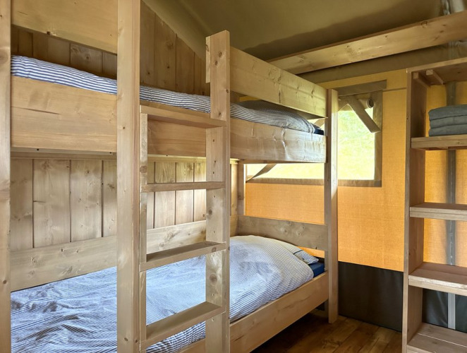 Letti a castello in legno in una tenda glamping al Domaine La Barbe, Francia, ambiente rustico e accogliente.