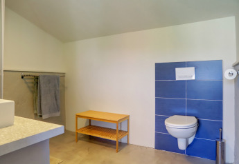 Badezimmer im Glamping-Zelt Domaine La Barbe, Frankreich, mit Wandtoilette und schlichter Einrichtung.