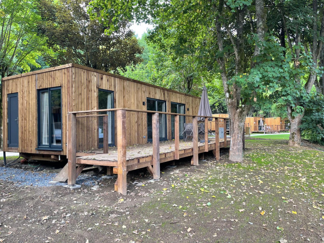 Houten lodge met ruim terras en tuinmeubilair, omgeven door bomen bij Ecolodge XXL TERRAS.