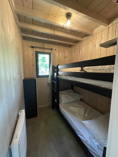 Kleine houten kamer met stapelbedden en raam in Ecolodge XXL TERRAS, Hameau de l'Ourthe, België.