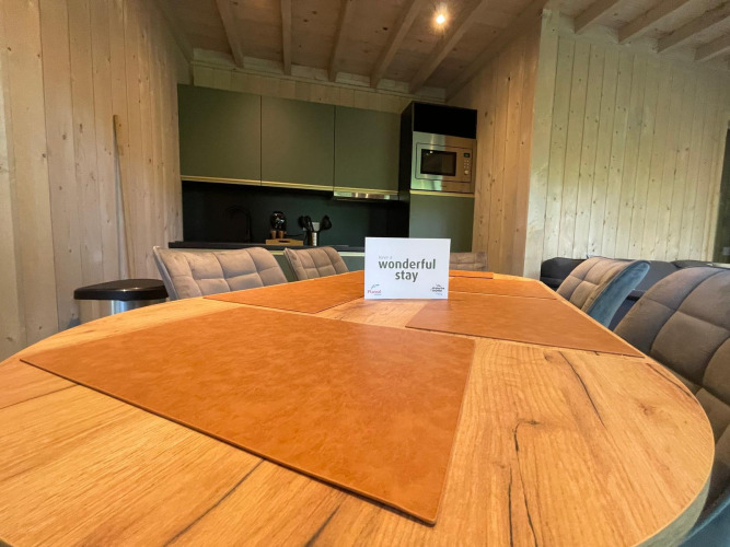 Mesa de comedor de madera con manteles individuales y tarjeta de bienvenida en Ecolodge XXL TERRAS, Bélgica