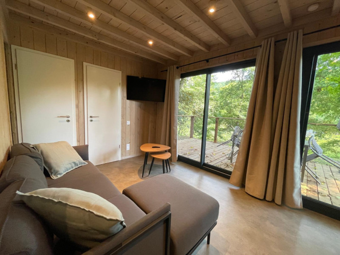 Moderne woonkamer in Ecolodge XXL TERRAS, Hameau de l'Ourthe, België met bank, tv en terraszicht.