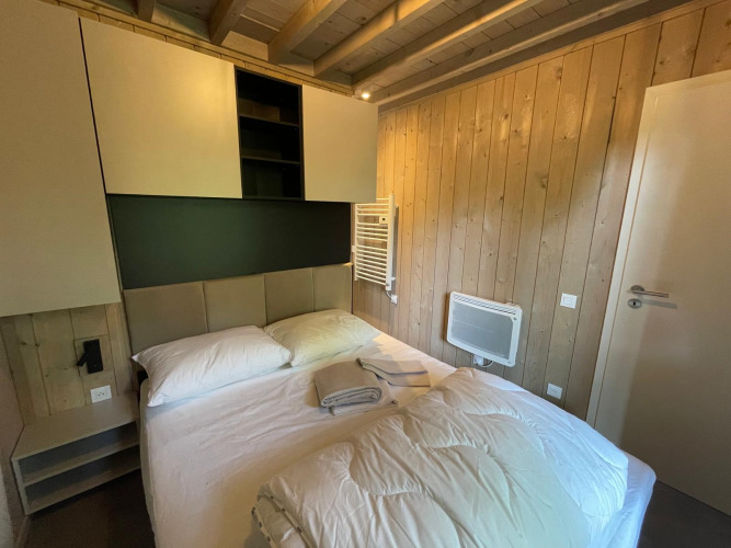 Dormitorio en Ecolodge XXL TERRAS en Hameau de l’Ourthe, Bélgica, con cama doble, paredes de madera y estilo moderno.