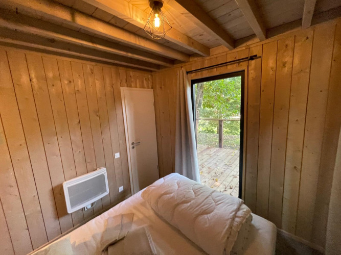 Dormitorio de la Ecolodge XXL TERRAS en Hameau de l'Ourthe, Bélgica, con paredes de madera y acceso a terraza.