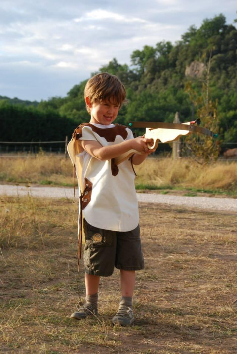 Jeune garçon jouant avec une arbalète en bois au Flower Camping La Sagne, Nouvelle-Aquitaine, France.