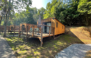 Eco Lodge au Hameau de l'Ourthe en Belgique, un chalet en bois avec terrasse entouré de verdure.