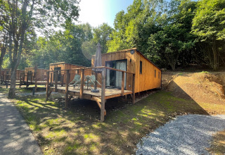 Eco Lodge ved Hameau de l'Ourthe i Belgien, en hyggelig træhytte med terrasse omgivet af grøn natur.