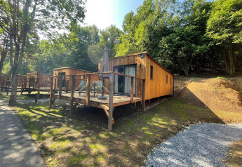 Eco Lodge bij Hameau de l'Ourthe in België, een houten huisje met terras omgeven door groen.