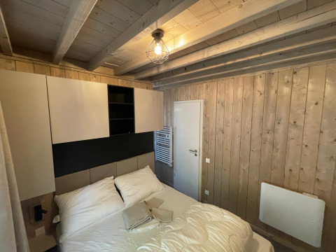 Soveværelse i Eco Lodge på Hameau de l'Ourthe, Belgien, med træpaneler, dobbeltseng og moderne skab.