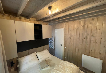 Slaapkamer in Eco Lodge bij Hameau de l’Ourthe, België, met houten wanden, bed en opbergkasten.