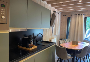 Moderne keuken en eetruimte in Eco Lodge bij Hameau de l'Ourthe, België, met natuurlijke houten accenten.