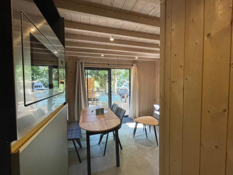 Indvendig udsigt af Eco Lodge på Hameau de l'Ourthe i Belgien med trævægge og store vinduer mod naturen.