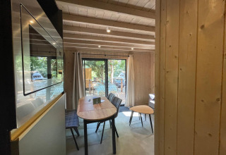 Indvendig udsigt af Eco Lodge på Hameau de l'Ourthe i Belgien med trævægge og store vinduer mod naturen.
