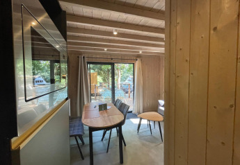 Interieur van Eco Lodge bij Hameau de l'Ourthe in België met houten wanden en zicht op terras en natuur.