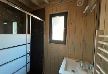 Moderne badkamer met houten wanden, douche, raam en wastafel bij Eco Lodge in Hameau de l'Ourthe, België.