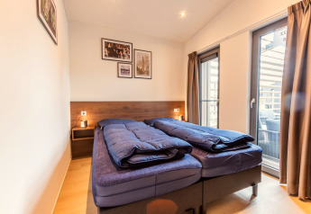 Moderne slaapkamer met twee eenpersoonsbedden en glazen deuren bij Cube Split Hottub, EuroParcs Enkhuizer Strand.