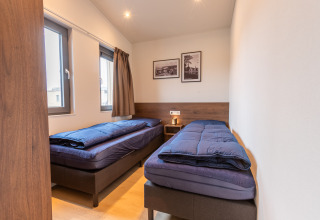 Due letti singoli con copriletto blu scuro in una stanza luminosa al Cube Split Hottub, EuroParcs Enkhuizer Strand.