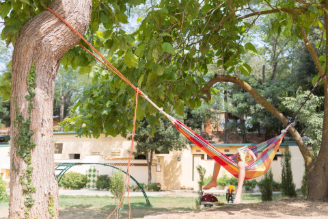 Persona che si rilassa su un'amaca colorata tra alberi al Camping Begur, Catalogna, Spagna.