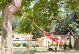 Persona che si rilassa su un'amaca colorata tra alberi al Camping Begur, Catalogna, Spagna.
