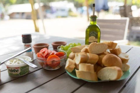 Petit-déjeuner avec pain, tomates, raisins, huile et fromage frais sur table au Camping Begur, Catalogne.