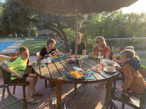 A family shares a meal outdoors at a table in Camping Begur, a holiday park in Catalonia, Spain.
