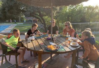 A family shares a meal outdoors at a table in Camping Begur, a holiday park in Catalonia, Spain.