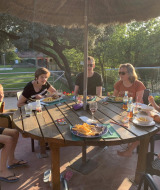 En familie nyder et måltid sammen udendørs ved Camping Begur feriepark i Catalonien, Spanien.
