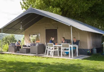 Gezin geniet buiten bij een luxe safaritent met terras op Camping Begur in Spanje