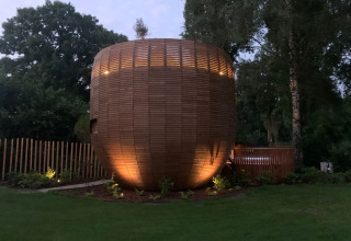 Træbeklædt tiny house ved navn The Nutshell med spabad og sauna i en grøn park i Holland, aftenstemning.