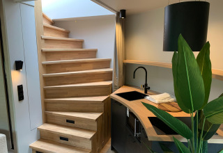 Moderne trappe og lille køkken med grøn plante i The Nutshell, tiny house i Nederlandene.
