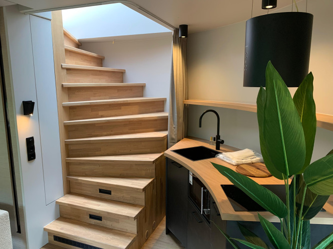 Escalera de madera y pequeña cocina en The Nutshell, tiny house en Den Blanken, Países Bajos.