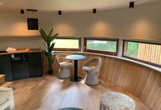 Interior of The Nutshell tiny house with round table, chairs, and windows at Recreation Park Den Blanken.