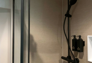 Modern shower inside The Nutshell tiny house at Recreation Park Den Blanken, Netherlands, with dispensers.