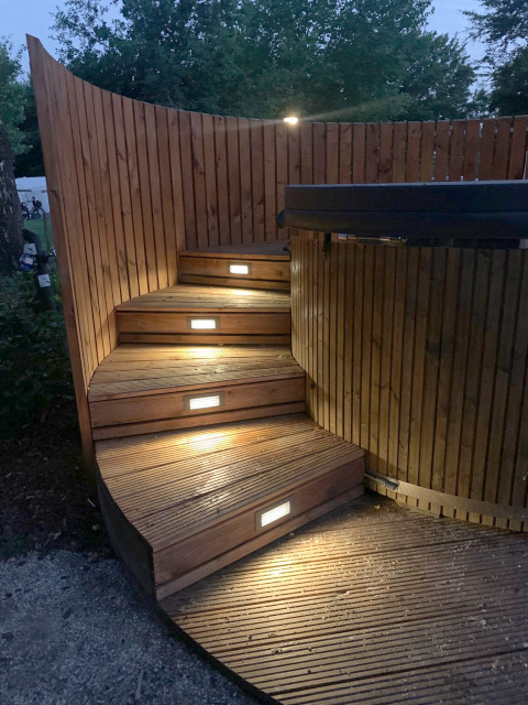 Curved wooden steps with embedded lights leading to a hot tub at The Nutshell in Den Blanken, Netherlands.