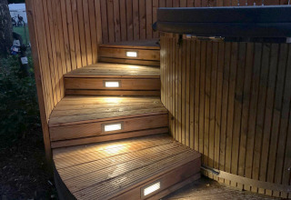 Curved wooden steps with embedded lights leading to a hot tub at The Nutshell in Den Blanken, Netherlands.