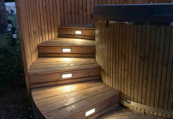 Beleuchtete Holztreppe und Whirlpool im Freien bei The Nutshell im Recreation Park Den Blanken, Niederlande.