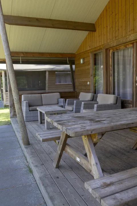 Covered wooden veranda at Safarilodge deluxe, Familievakantiepark Krieghuusbelten, Netherlands, with seating.