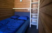 Indvendigt billede af en safarilodge deluxe med trævægge, en dobbeltseng og stige, Familievakantiepark Krieghuusbelten.