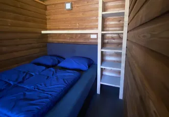 Interno di una tenda Safarilodge deluxe con pareti in legno, letto matrimoniale e scala a Krieghuusbelten, Paesi Bassi.