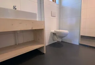 Moderne badeværelse med ophængt toilet, trævask og lille vindue i Safarilodge deluxe i Holland.